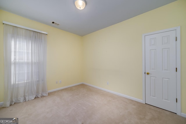 spare room featuring carpet floors, visible vents, and baseboards