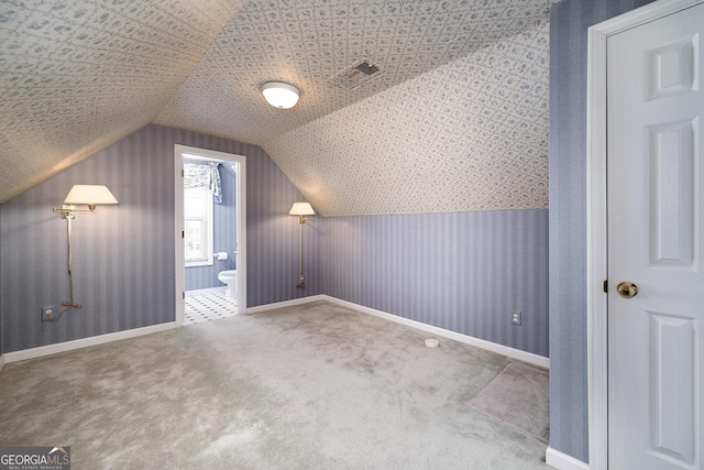 additional living space with lofted ceiling, carpet flooring, visible vents, baseboards, and wallpapered walls