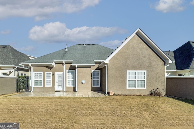 rear view of house with a yard, a patio area, fence, and stucco siding