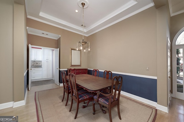 dining area with a notable chandelier, light wood finished floors, baseboards, and crown molding