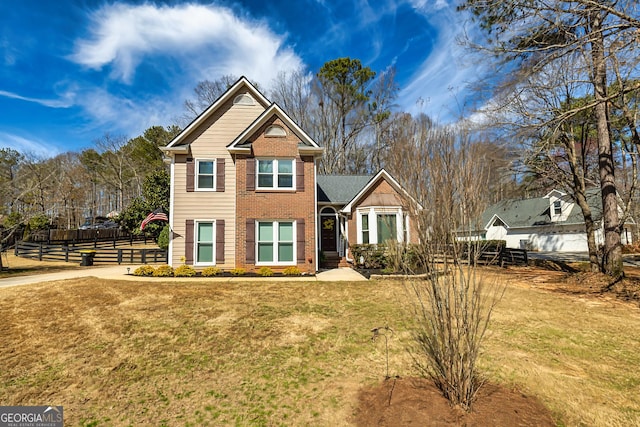 traditional-style house with brick siding, a front yard, and fence