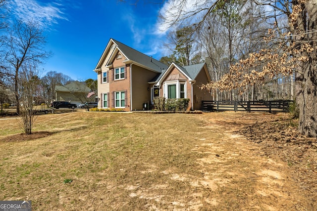 traditional-style home with fence, a front lawn, and brick siding