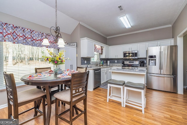 kitchen featuring stainless steel appliances, light wood-style flooring, visible vents, and decorative backsplash