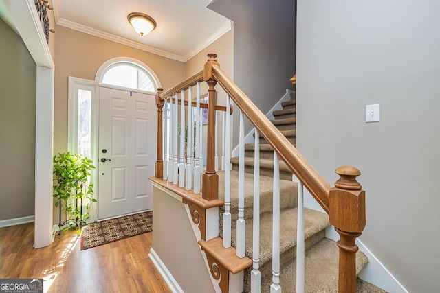 foyer entrance featuring stairs, ornamental molding, wood finished floors, and baseboards