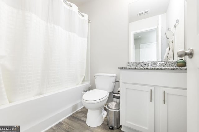 full bath featuring visible vents, toilet, wood finished floors, shower / bath combo with shower curtain, and vanity