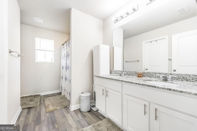 bathroom with double vanity, a sink, baseboards, and wood finished floors