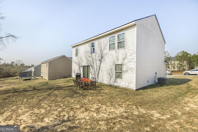 back of house featuring a yard, a trampoline, and central air condition unit