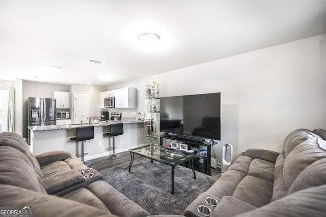 living room featuring baseboards, visible vents, and dark wood-type flooring