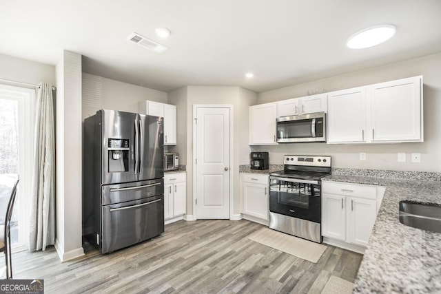 kitchen featuring visible vents, appliances with stainless steel finishes, and white cabinets