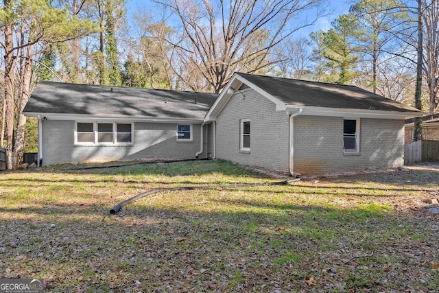 back of house featuring a lawn and brick siding