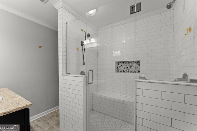 full bathroom featuring wood finished floors, vanity, baseboards, ornamental molding, and a stall shower