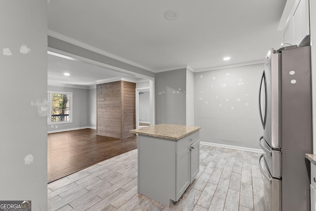 kitchen with wood tiled floor, open floor plan, crown molding, and freestanding refrigerator