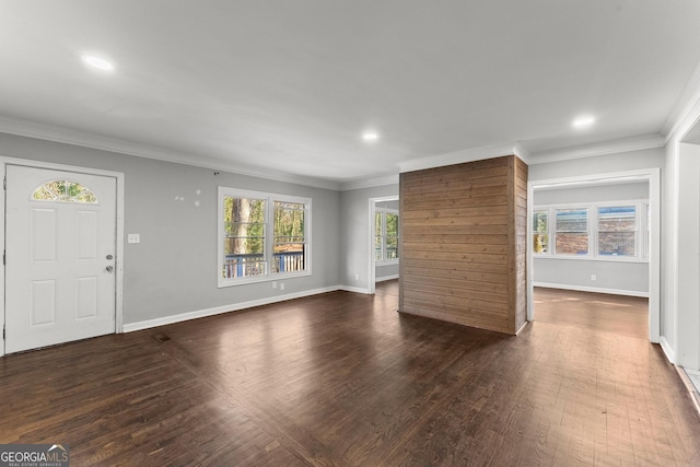 unfurnished living room with a healthy amount of sunlight, ornamental molding, and dark wood finished floors