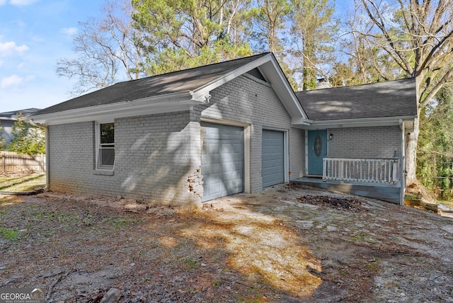 view of side of home featuring a garage, driveway, a chimney, fence, and brick siding