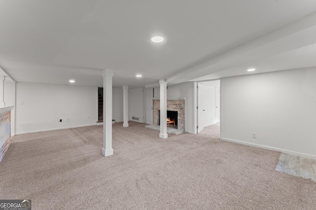 finished basement featuring light carpet, visible vents, baseboards, a brick fireplace, and recessed lighting