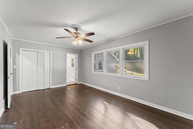 unfurnished bedroom featuring dark wood-style floors, a closet, baseboards, and crown molding