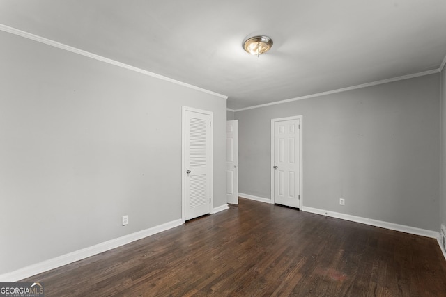 empty room featuring dark wood-style floors, crown molding, and baseboards