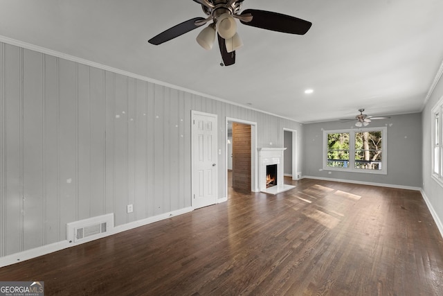 unfurnished living room with wood finished floors, a fireplace with flush hearth, baseboards, visible vents, and crown molding