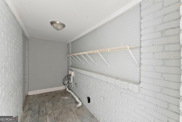 laundry room featuring brick wall, laundry area, wood finished floors, and hookup for a washing machine