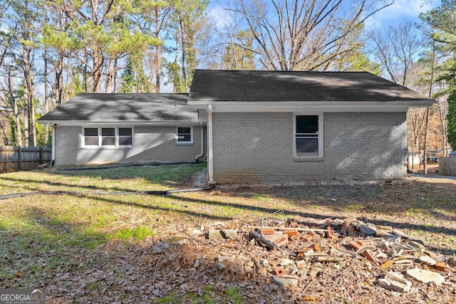 exterior space featuring brick siding, fence, and a lawn