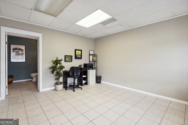 office space featuring a paneled ceiling, light tile patterned floors, visible vents, and baseboards