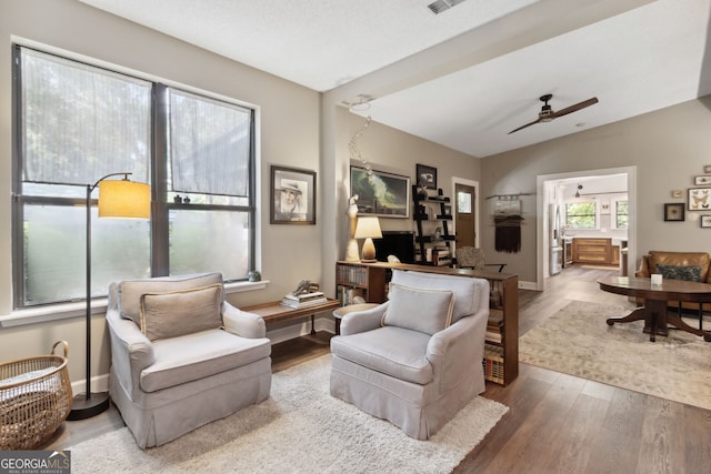 living room featuring ceiling fan, wood finished floors, lofted ceiling, and baseboards