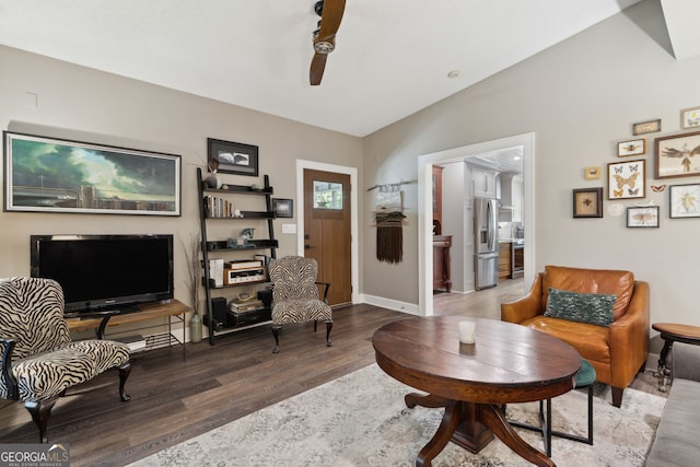 living area featuring lofted ceiling, baseboards, and wood finished floors