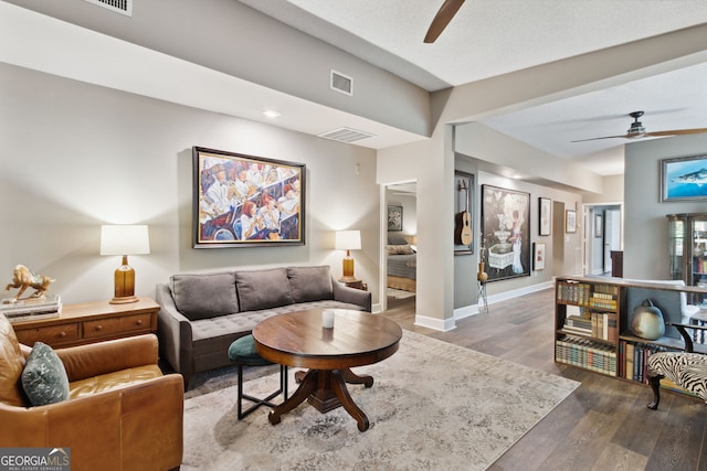 living room with baseboards, wood finished floors, visible vents, and a ceiling fan