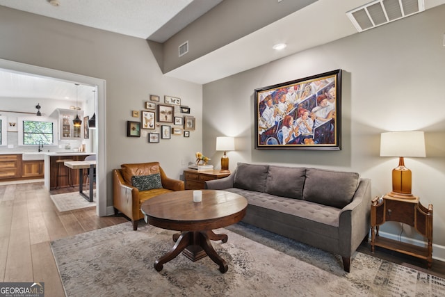 living room featuring wood-type flooring, visible vents, and recessed lighting