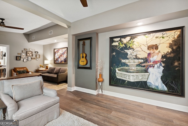 living area with vaulted ceiling with beams, wood finished floors, a ceiling fan, and baseboards