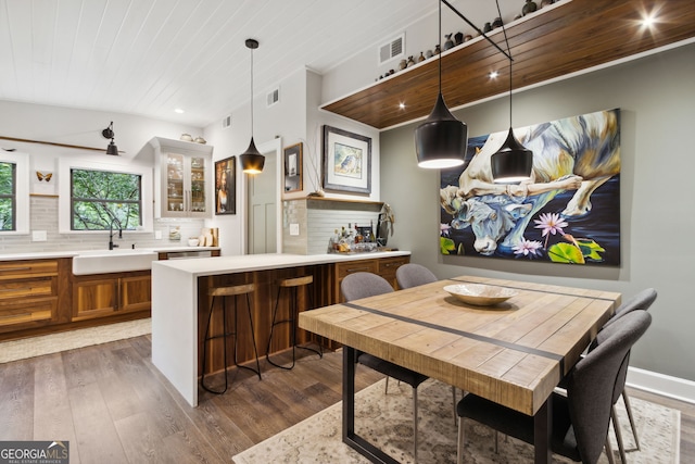 kitchen with tasteful backsplash, brown cabinetry, a sink, and dark wood-style floors