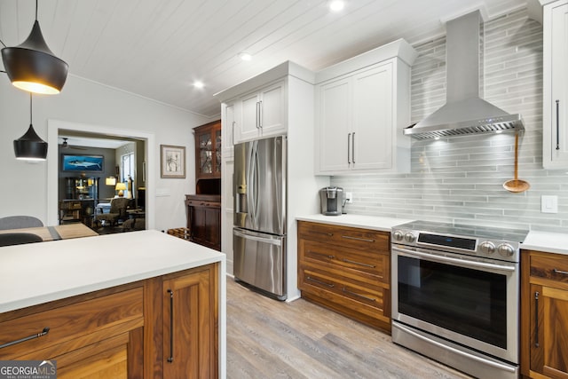 kitchen featuring decorative backsplash, wall chimney exhaust hood, light wood-style flooring, appliances with stainless steel finishes, and white cabinetry