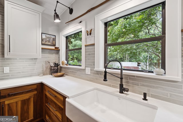 kitchen with white cabinets, decorative backsplash, a sink, and light countertops