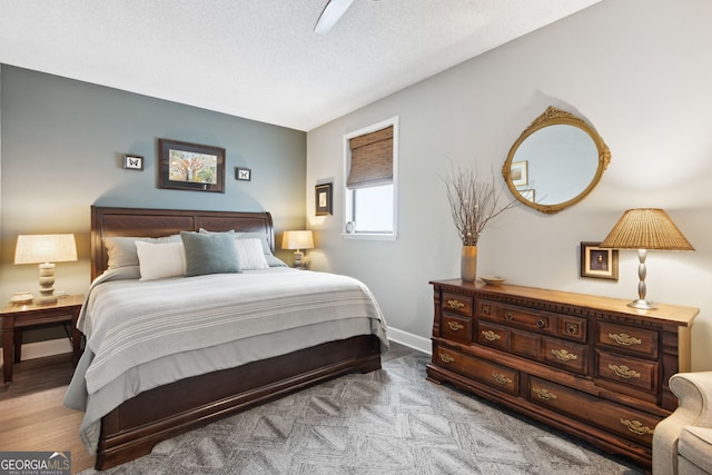 bedroom with a textured ceiling, baseboards, and wood finished floors