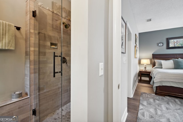 bathroom with a stall shower, visible vents, ensuite bath, wood finished floors, and a textured ceiling