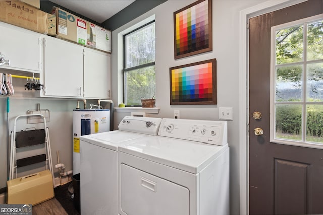 clothes washing area featuring a wealth of natural light, water heater, cabinet space, and washing machine and clothes dryer