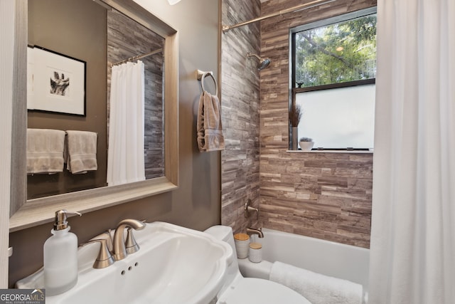 bathroom with toilet, shower / bathtub combination with curtain, and a sink