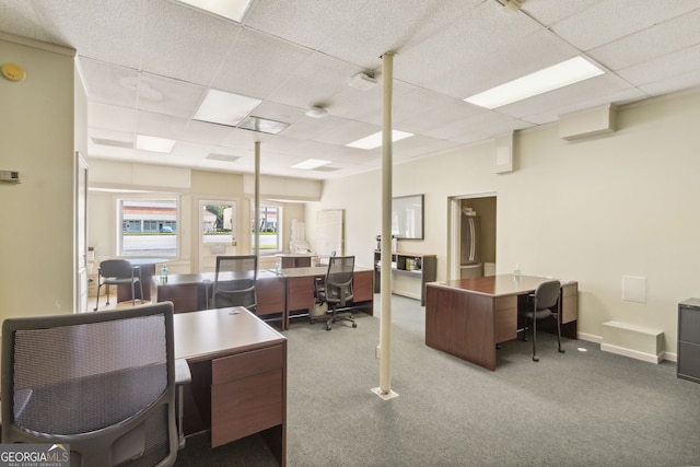 carpeted office space featuring a drop ceiling and baseboards