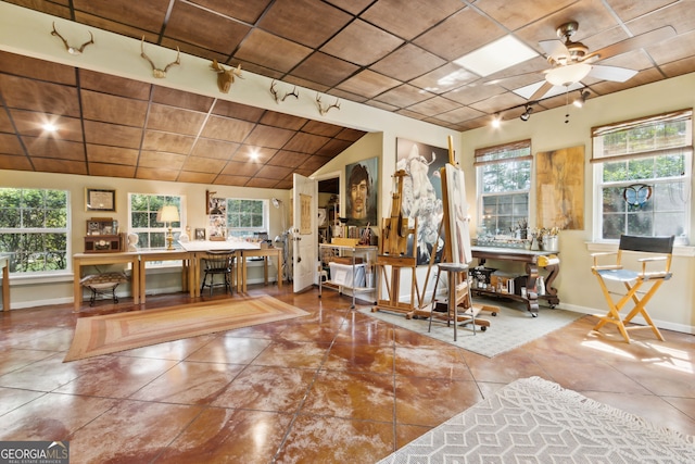 interior space with lofted ceiling, rail lighting, ceiling fan, and baseboards