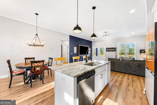 kitchen featuring a sink, white cabinetry, stainless steel dishwasher, light wood finished floors, and pendant lighting