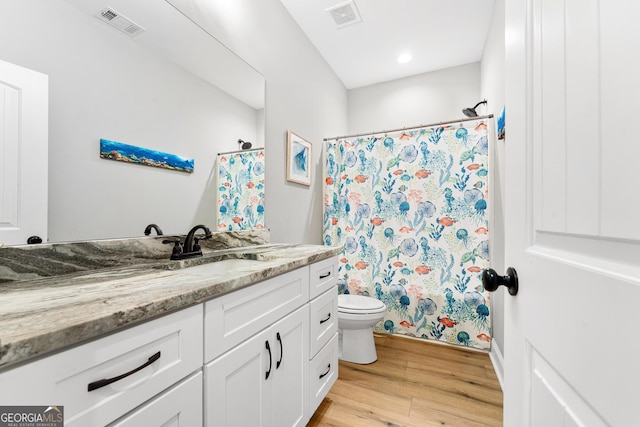 bathroom with visible vents, vanity, toilet, and wood finished floors