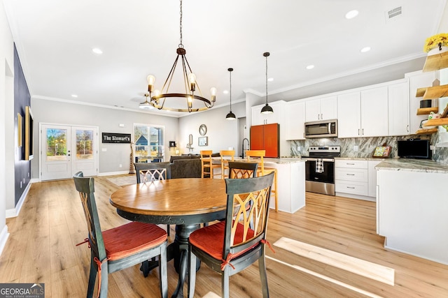 dining space with ornamental molding, visible vents, and light wood-style flooring