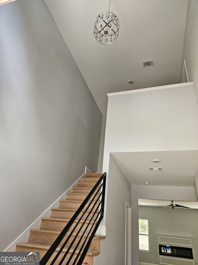 stairway with visible vents, ceiling fan, and baseboards