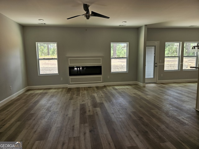 unfurnished living room with a healthy amount of sunlight, baseboards, and a glass covered fireplace