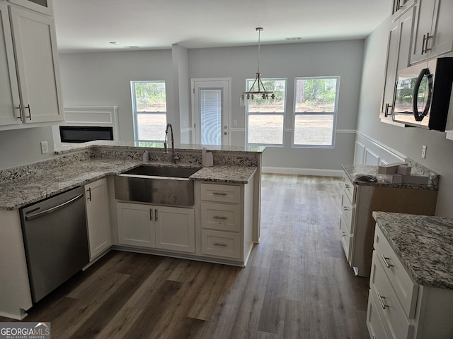 kitchen with a sink, a peninsula, light stone counters, and stainless steel dishwasher