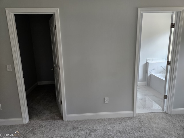 unfurnished bedroom with marble finish floor, ensuite bath, baseboards, and carpet