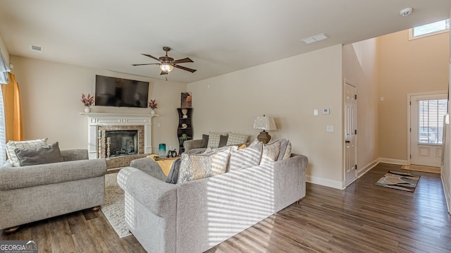 living room with baseboards, visible vents, a glass covered fireplace, ceiling fan, and wood finished floors