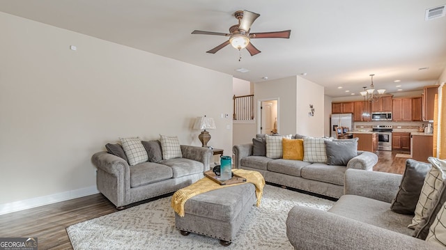 living room featuring recessed lighting, visible vents, light wood-style floors, baseboards, and ceiling fan with notable chandelier