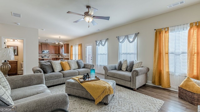 living area featuring a ceiling fan, light wood-type flooring, visible vents, and baseboards