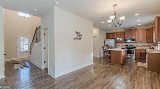 kitchen with stainless steel appliances, tasteful backsplash, light countertops, dark wood-type flooring, and a kitchen bar